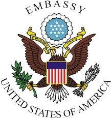 Seal of the United States Embassy featuring an eagle with shield, olive branch, and arrows.